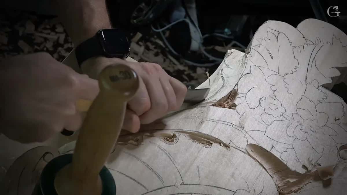 Gouge gripped hard, a green mallet standing beside it