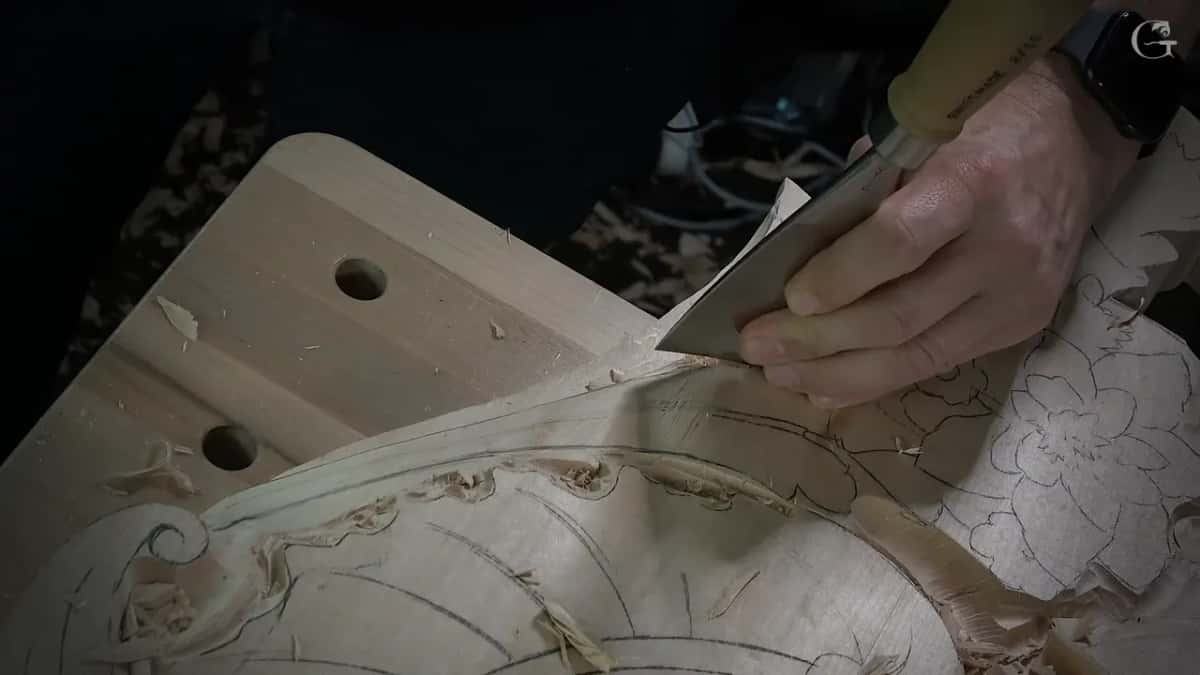 Hand pressing a very wide flat gouge into the edge of the leaf