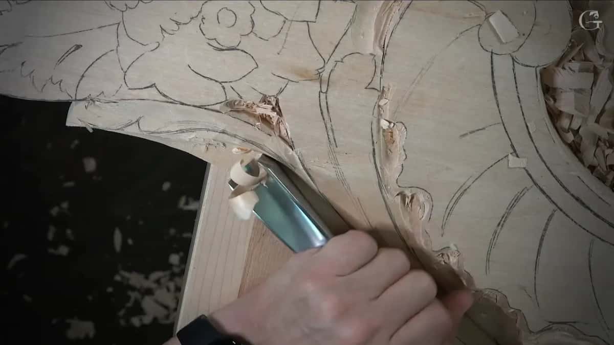Wide deep gouge riding the curve of the leaf over a bench top full of holes