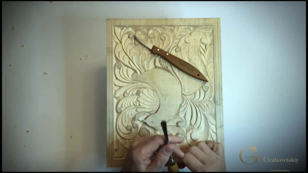 Blade laid down across the finished carving while the next tool gets explained.