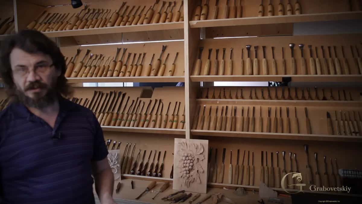 Five shelves of carving tools behind him.