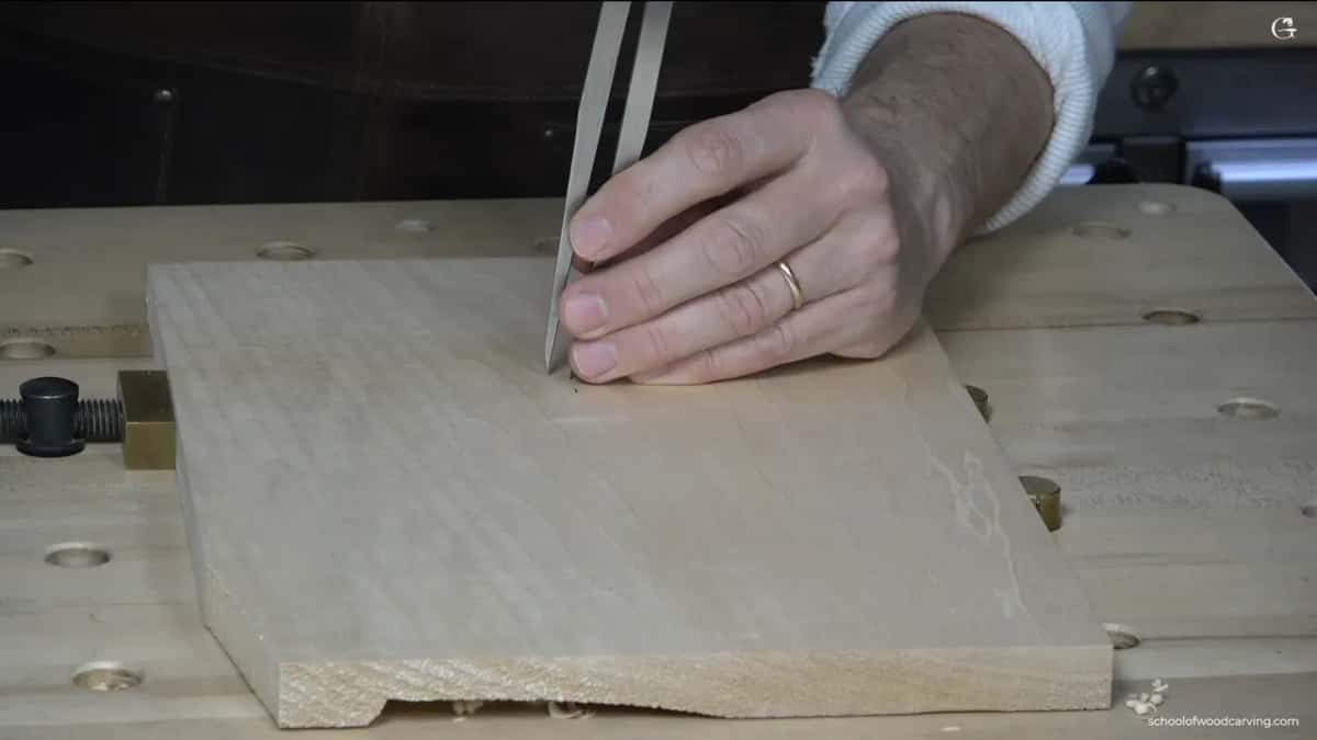 Bare basswood under the first caliper point, the other hand pressing down.