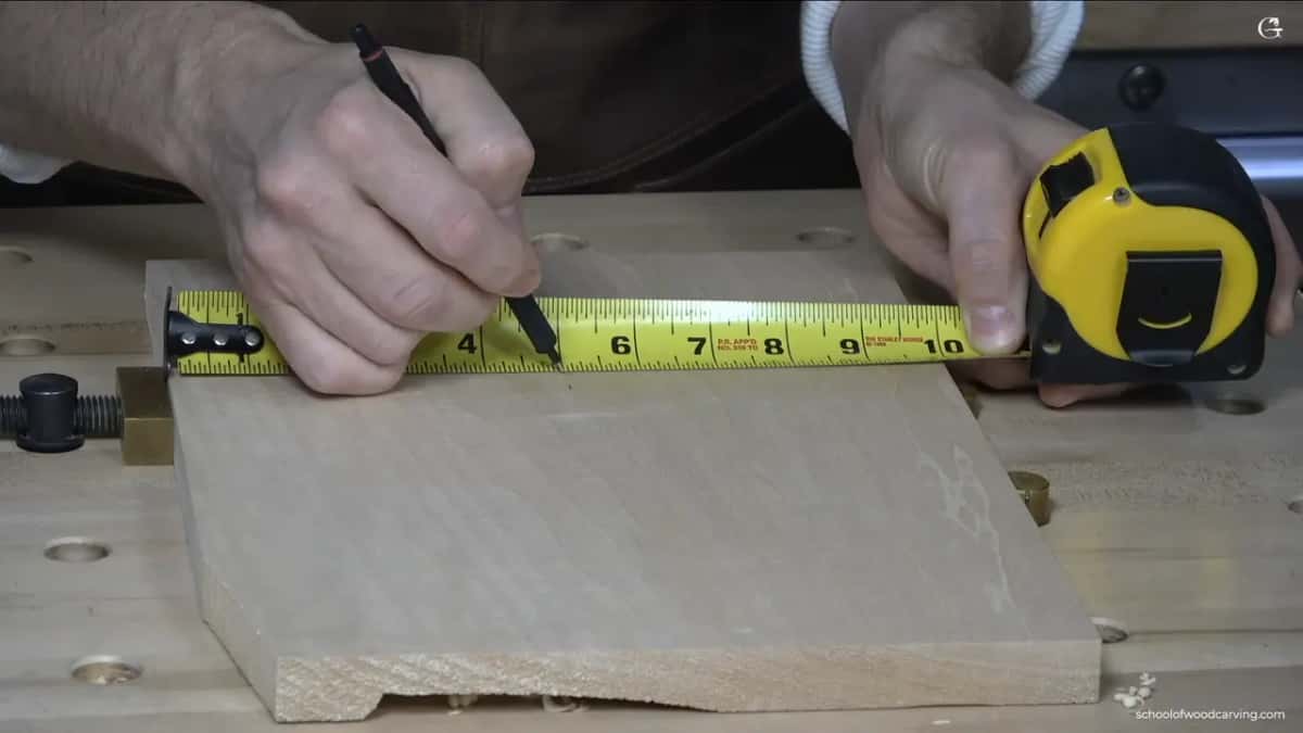 Marking the five inch point off a yellow tape measure, one hand on the case.
