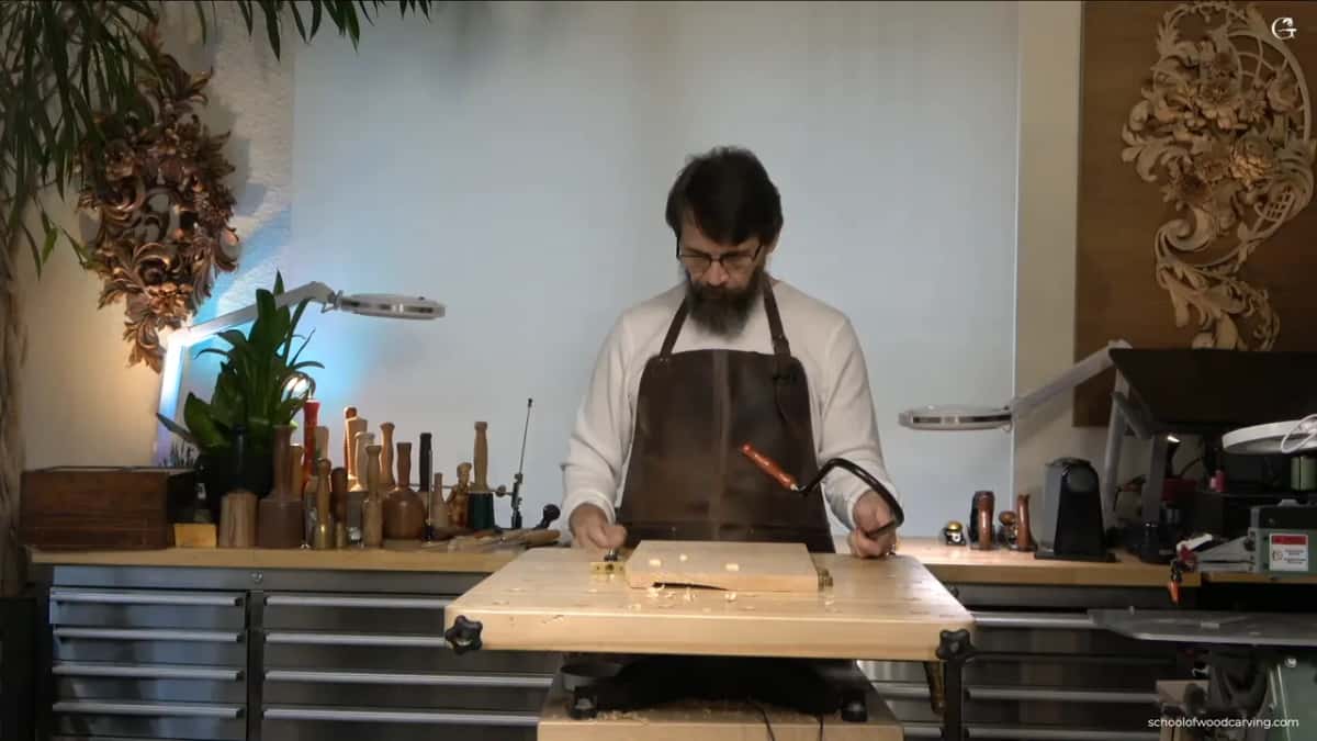 Fret saw in hand at the bench, sawing out the circle while the board rests on the tabletop.