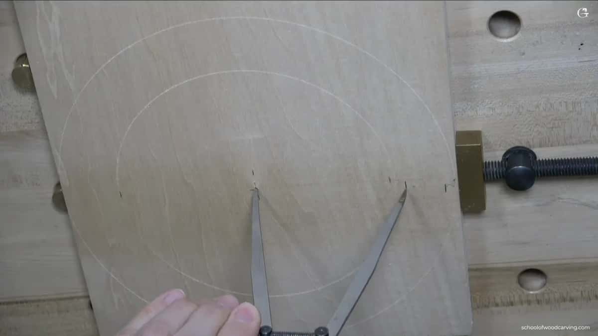 Seen from above, two rings scratched from one middle point, caliper legs and a hand at the bottom.