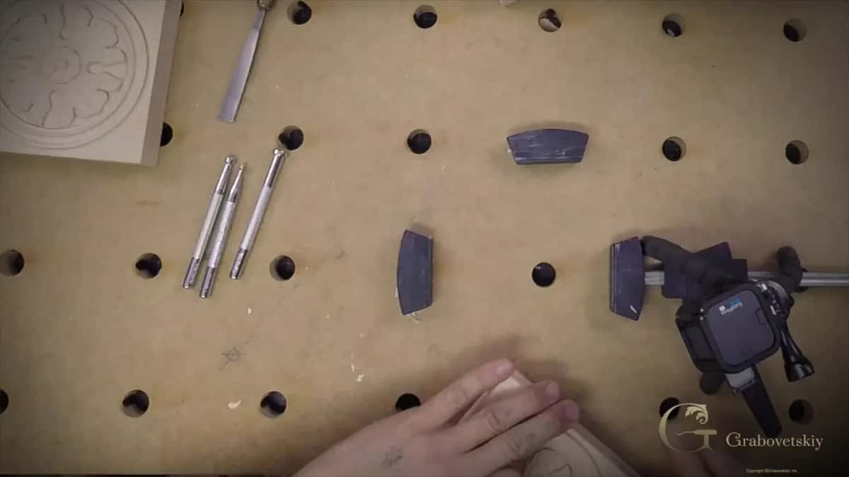 Three punches, a V tool and a finished rosette laid out on a drilled bench top
