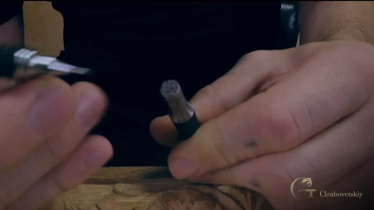 Small round punch held over a dark carved edge, texture upward