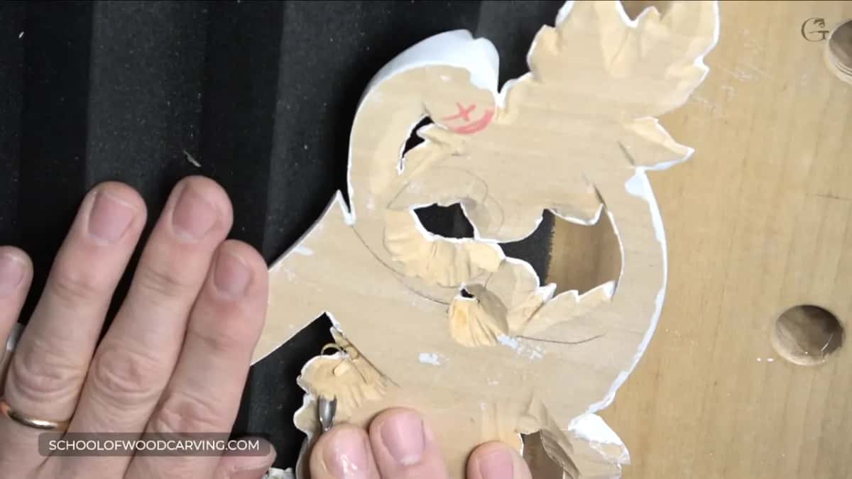 Primed carving lies face down on ribbed black studio foam as a small tool works its back