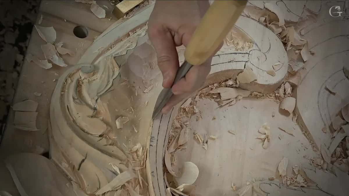 A narrow tool stands upright at the edge of the curved band while the ground beside it lies in chips