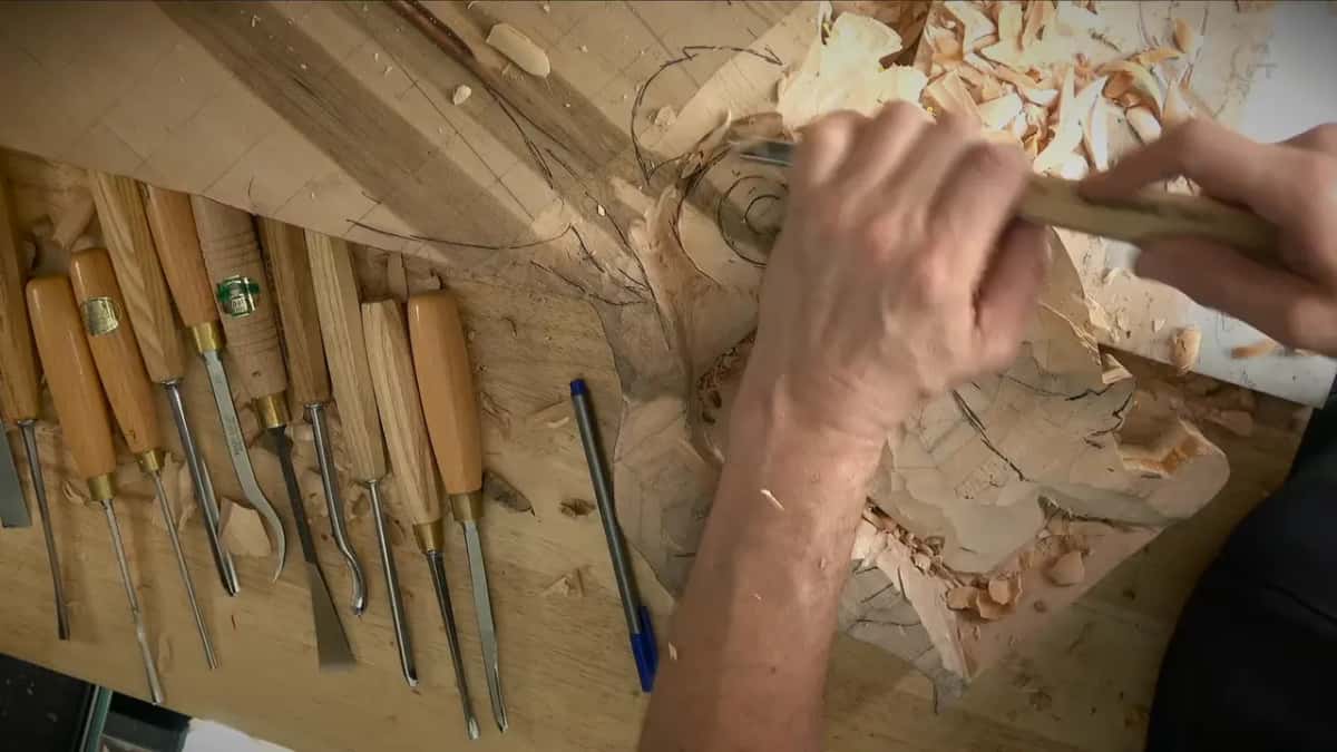 Two hands rolling a gouge around a scroll