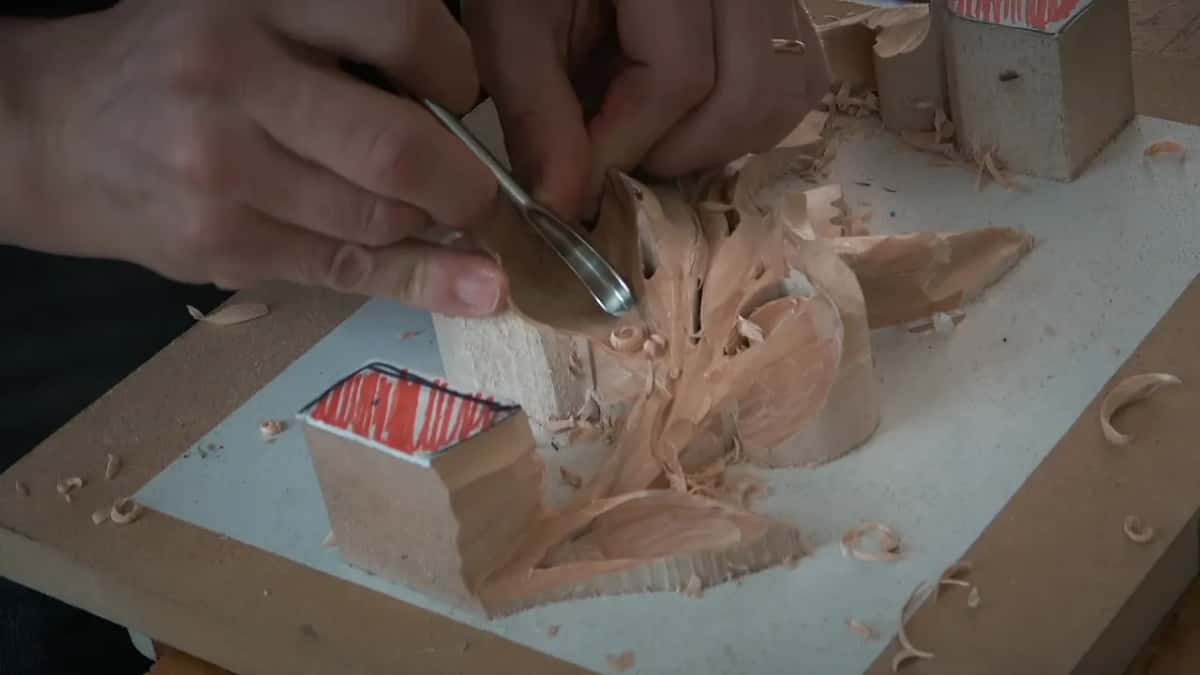 Both hands steer a spoon gouge across the lobe on the left