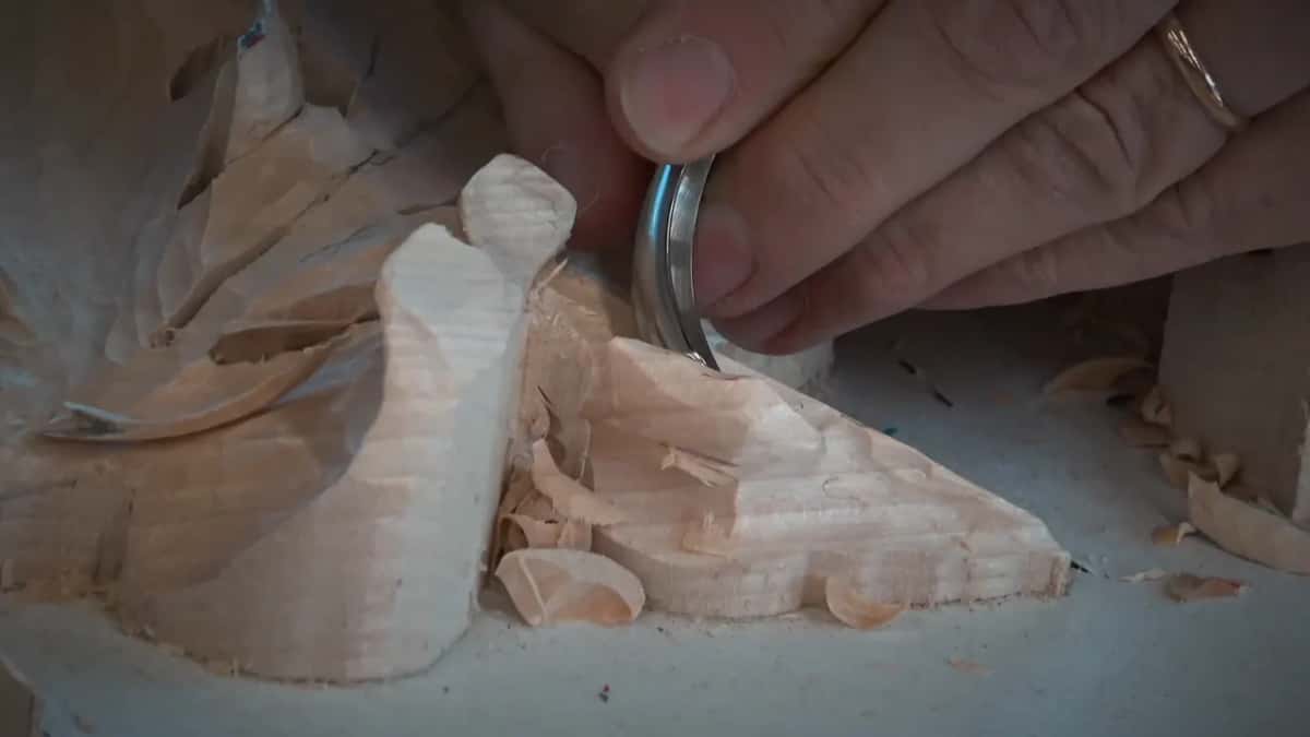 Pressed into the side of a tall lobe, a bent spoon tool leaves chips curling at its foot