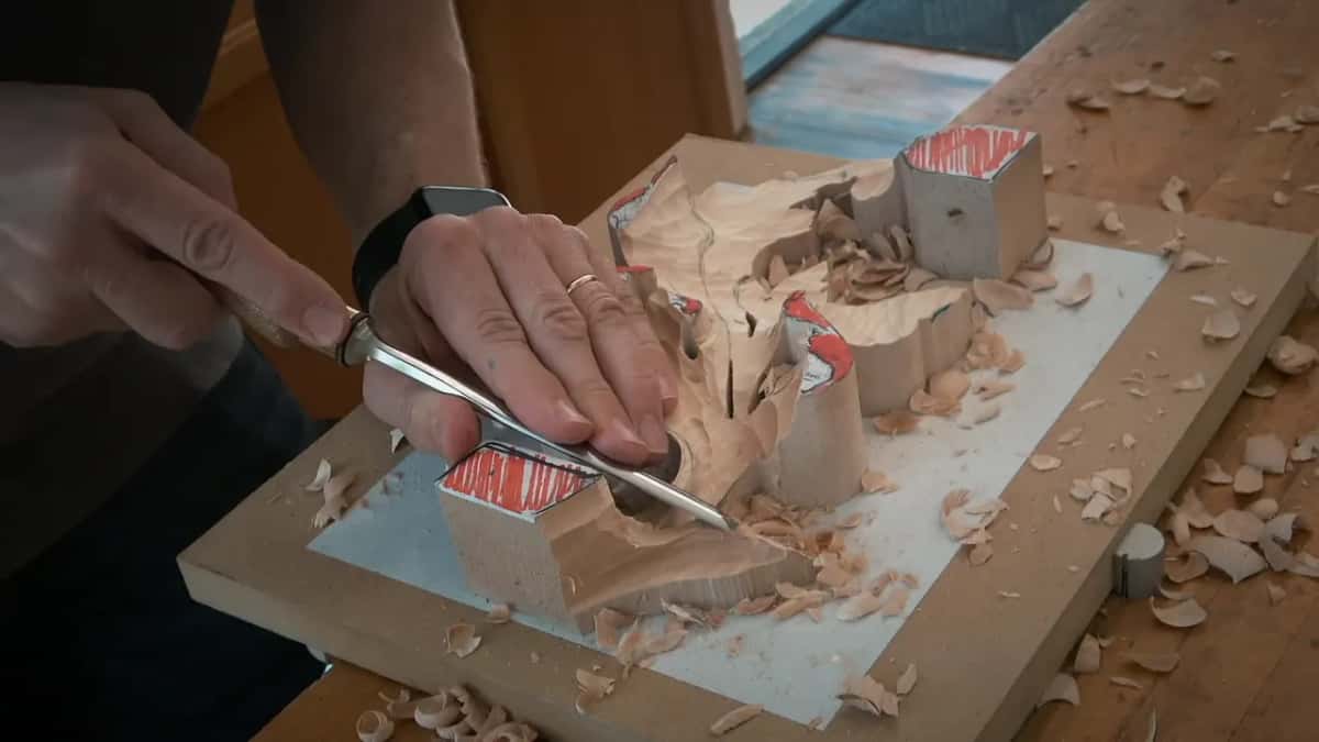 One hand flat on the blank, the other guiding a gouge along it