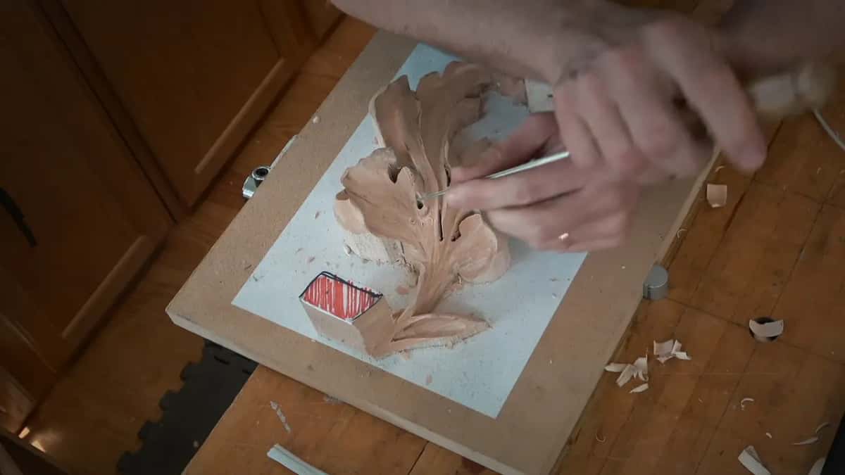From above, fingertips pinch a thin tool against the upper lobes while the other hand braces the work