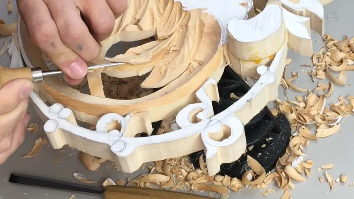 Flat chisel held under the leaves at the rim of the basket while a second tool lies on the bench