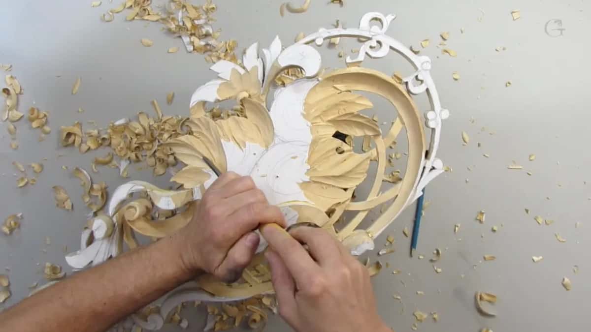 From overhead, two hands close together on a short tool near the middle, chips scattered on the left