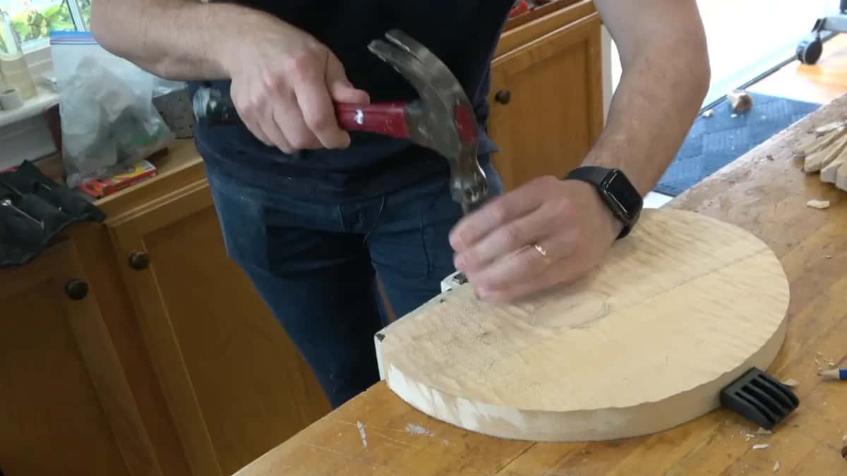 Hammer and nail near the edge of the round board