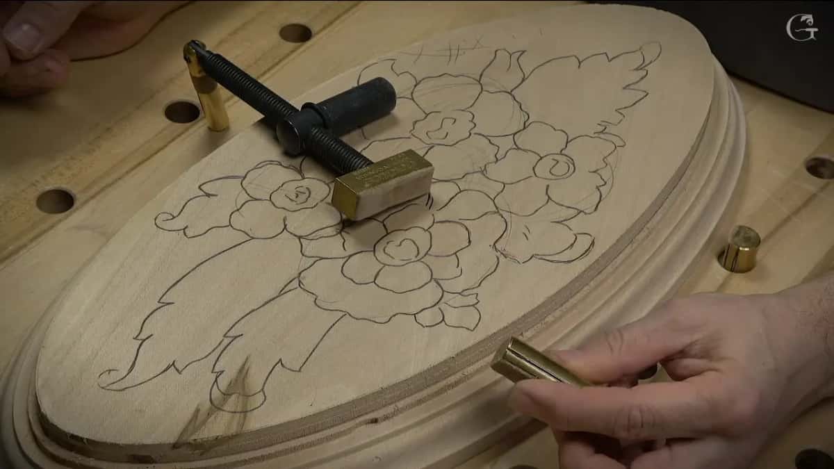 Brass pegs stand in the bench holes around an oval panel drawn with roses.