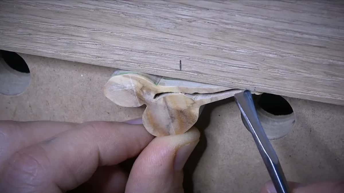 Olive wood piece braced against a pale oak block while a narrow blade goes in from the side.