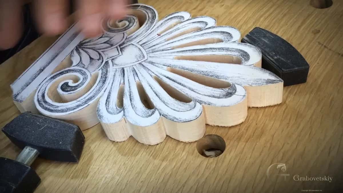 Dark pads hold the palmette at a slant on an oak bench while a hand blurs past.