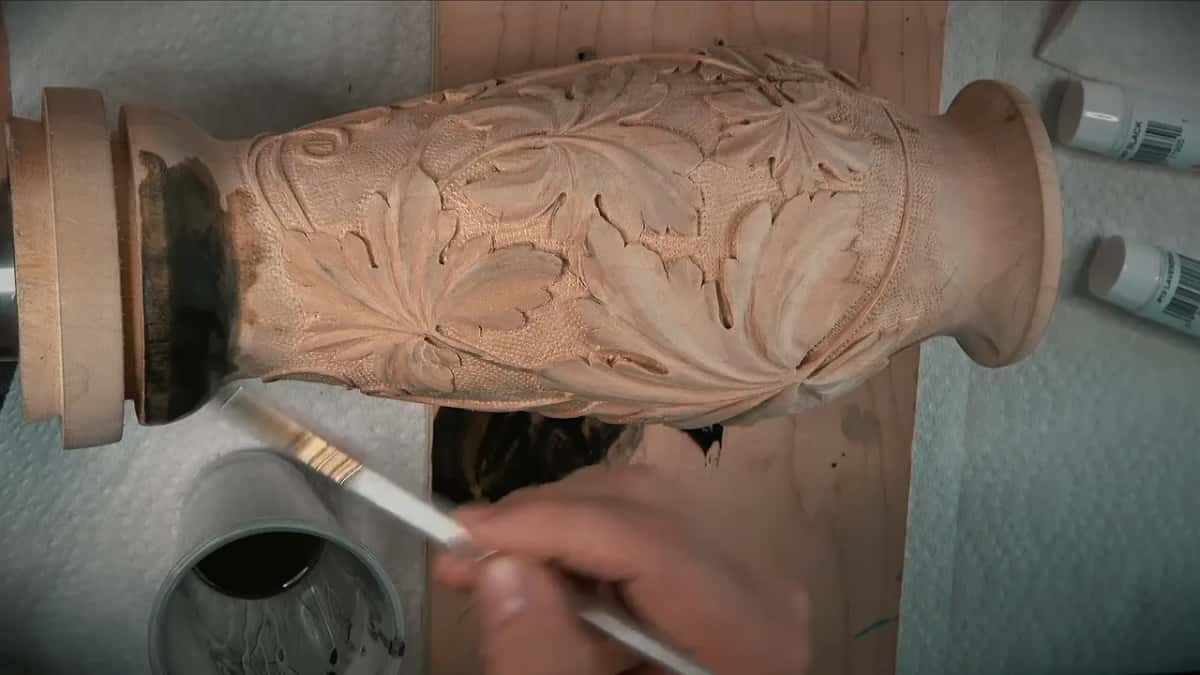 Flat brush laying black where the body meets the turned foot, a cup of stain below it