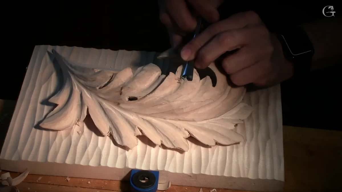 Both hands take a small tool across the side of the head, with the textured ground all around