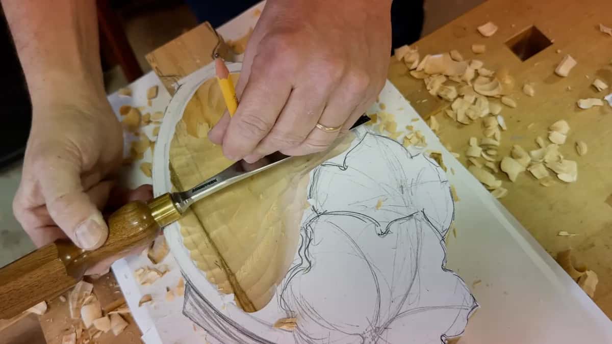 Both hands busy, a pencil stood in the hollow next to a gouge laid across the rim