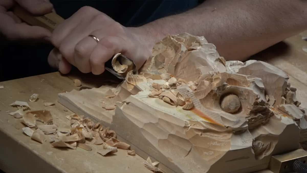 Both hands guide a gouge near the nut, side on