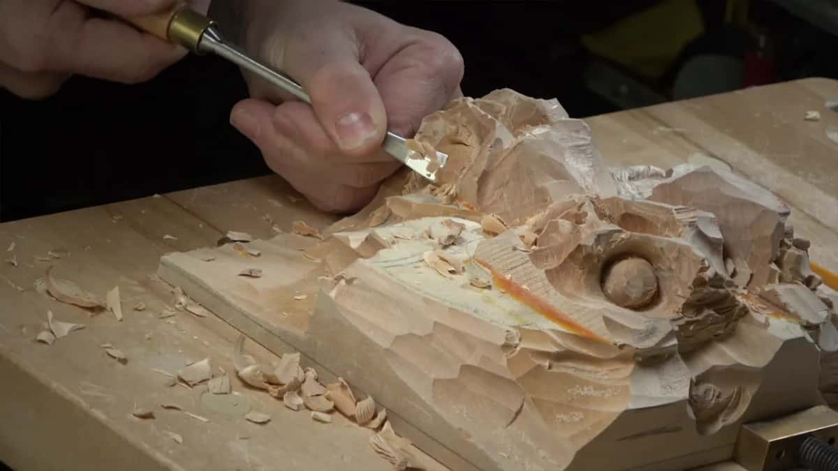 A narrow tool works next to the round nut, seen from the side