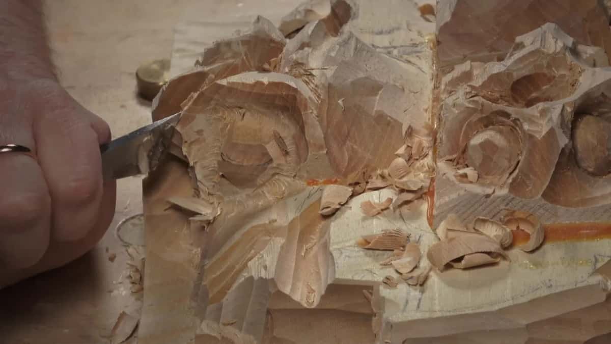 Close view of a flat skew blade in the side of the rough block, his fist around the handle