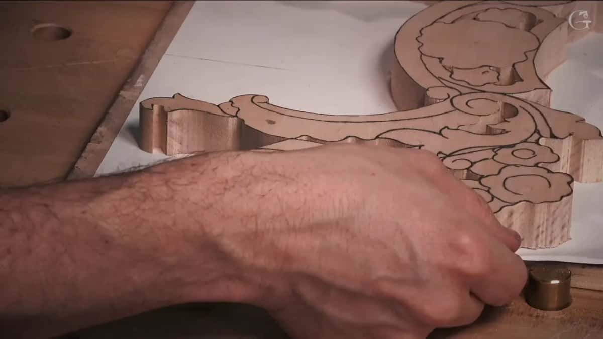 Forearm pressing the blank beside a brass peg