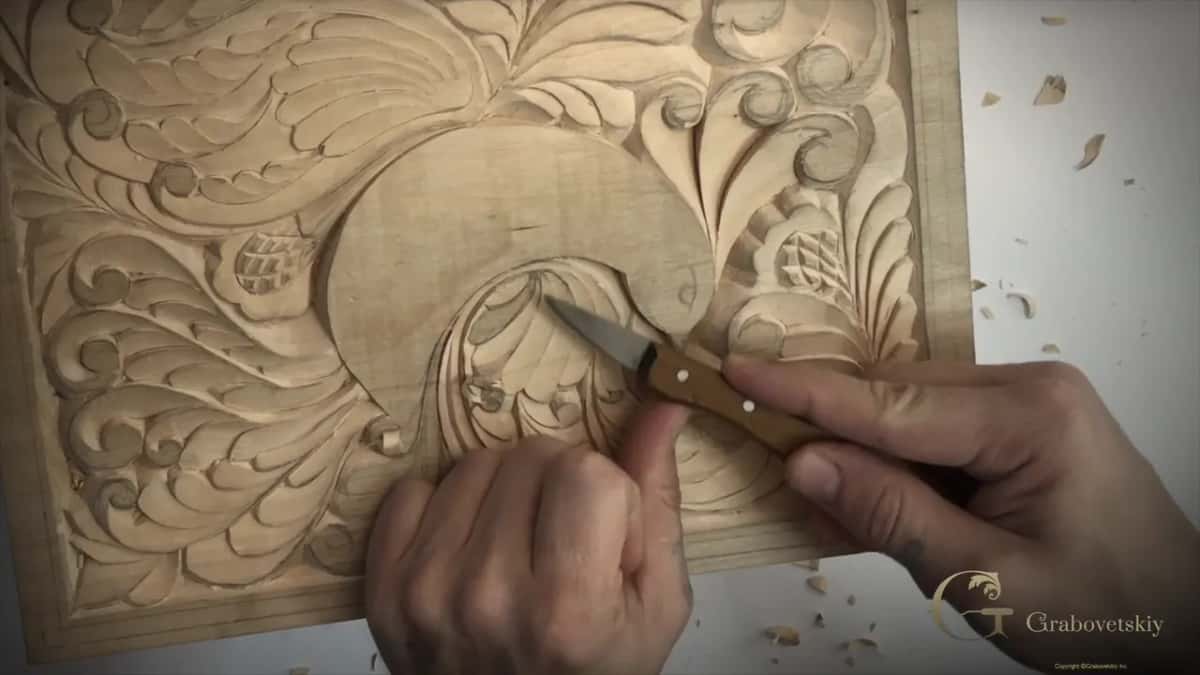 Right hand on a riveted knife handle and my left thumb behind the blade, both over the curl below the bird