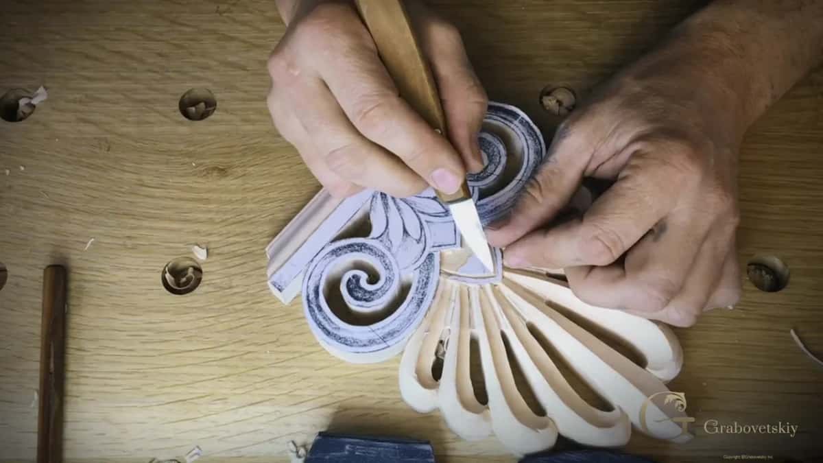 Knife held like a pen, working the center of the palmette.