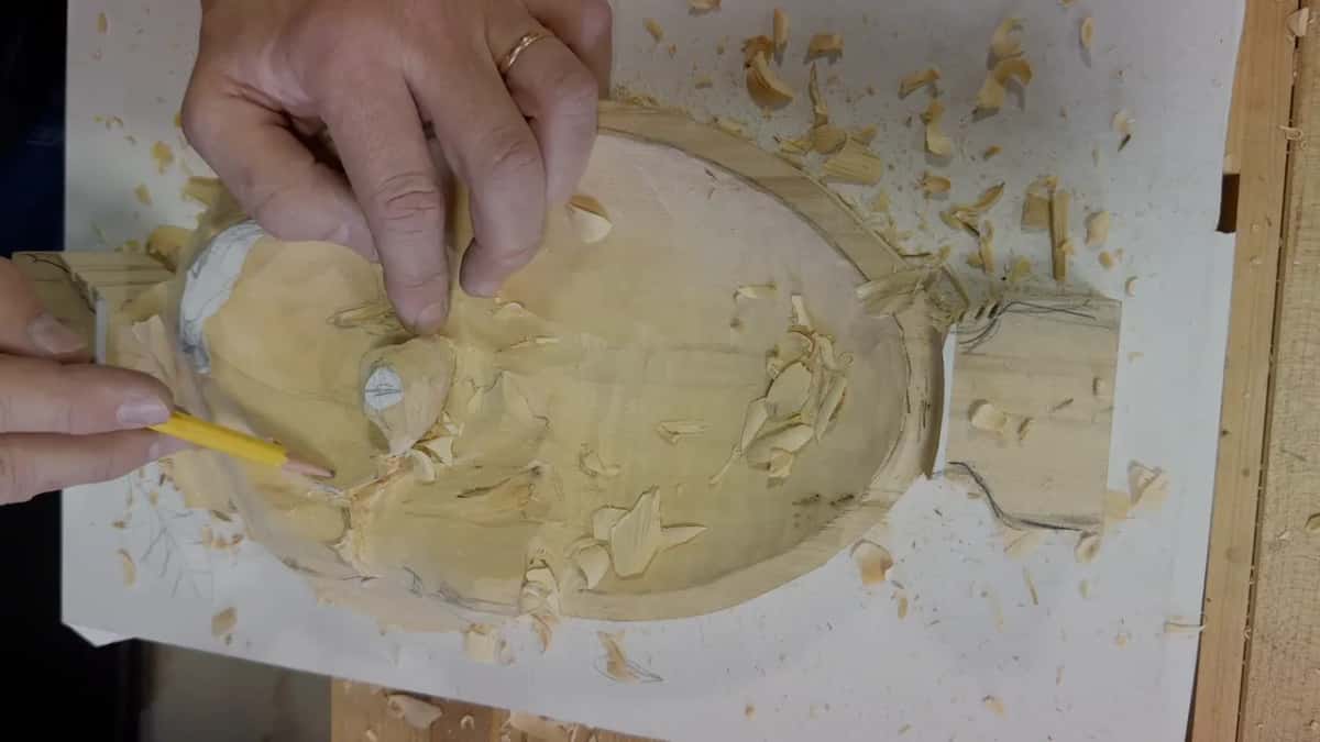 With one hand on the tray, the other holds a pencil against the lobe next to the eye