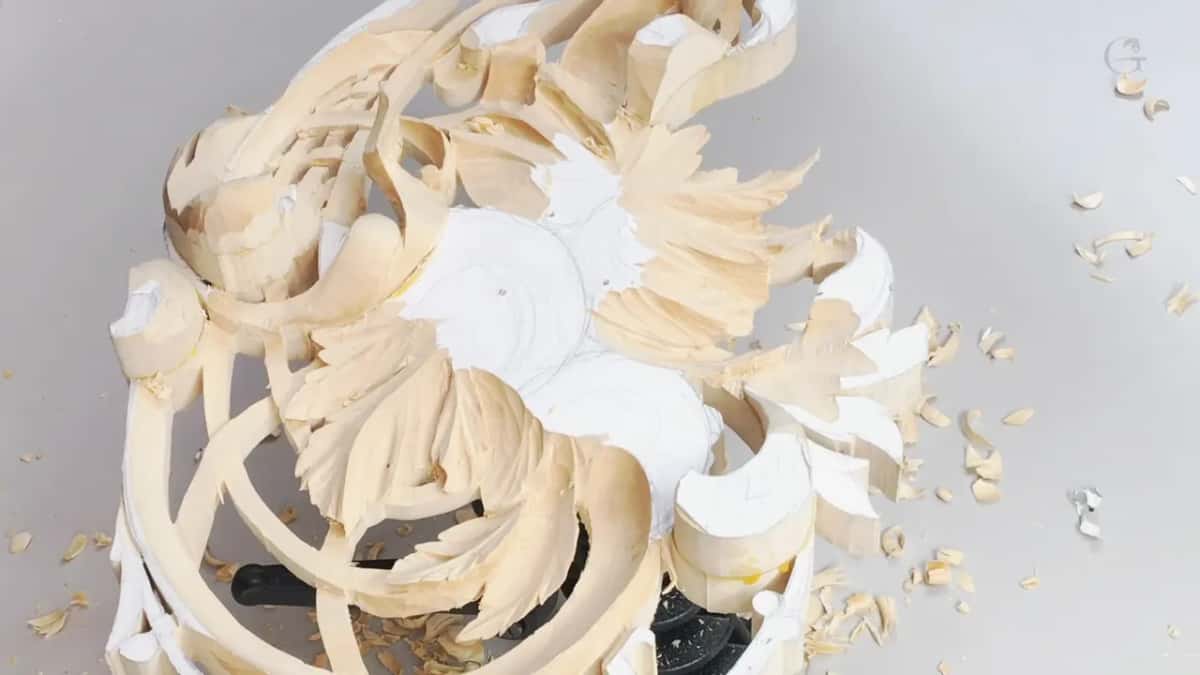 From above, carved leaves fan out around paper circles, with a lattice curling along the left side.