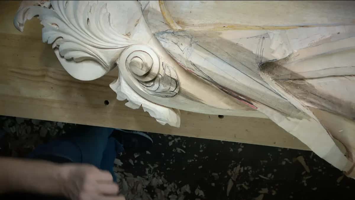 Large carved scroll on the bench, with a darker streak running through the pale wood.