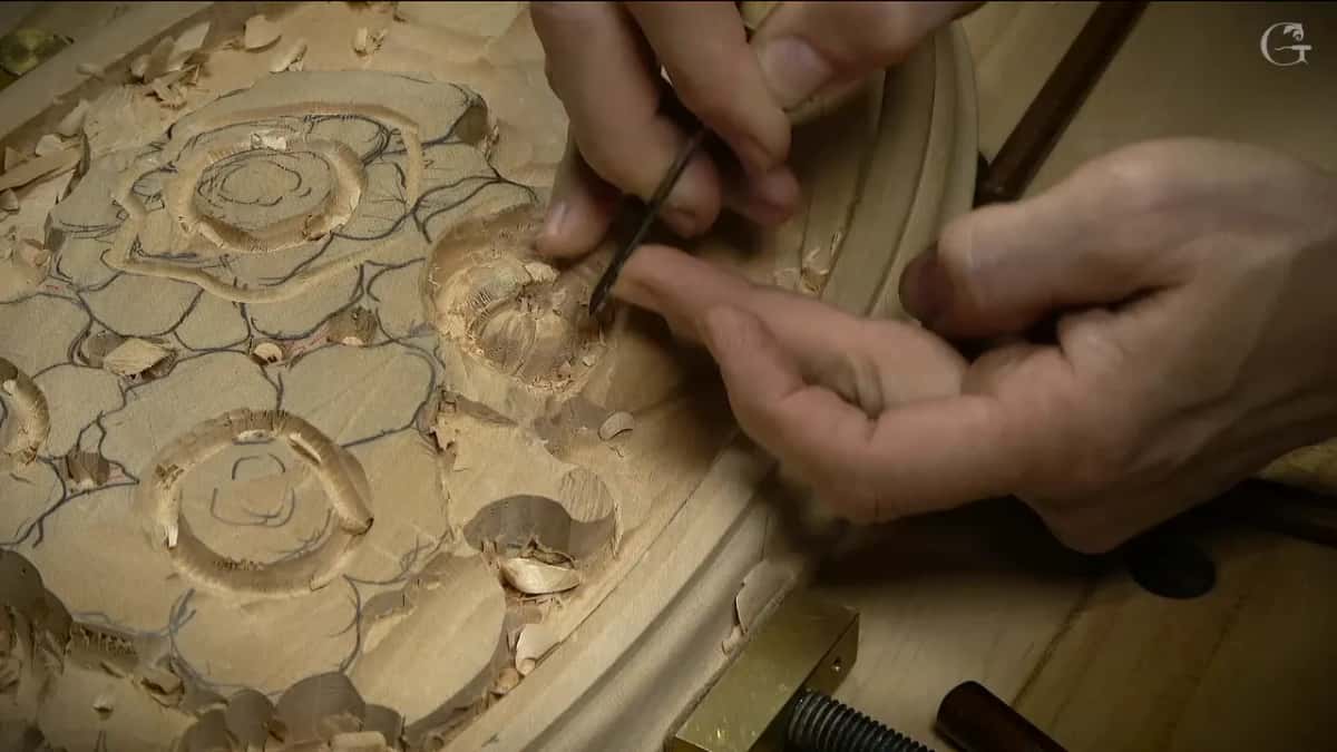 Both hands work a fine tool at the edge of one flower