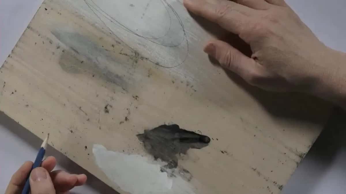 One hand drawing with a pencil over the board