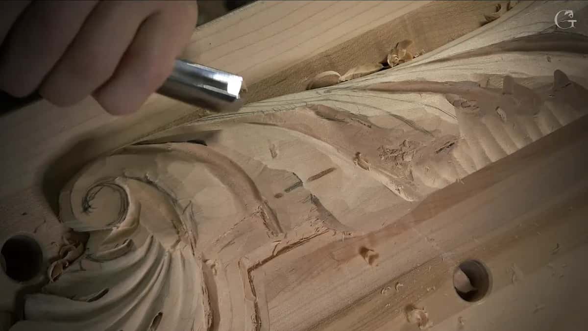 A silver tool hangs over the same rolled scroll, its handle hidden in a closed hand