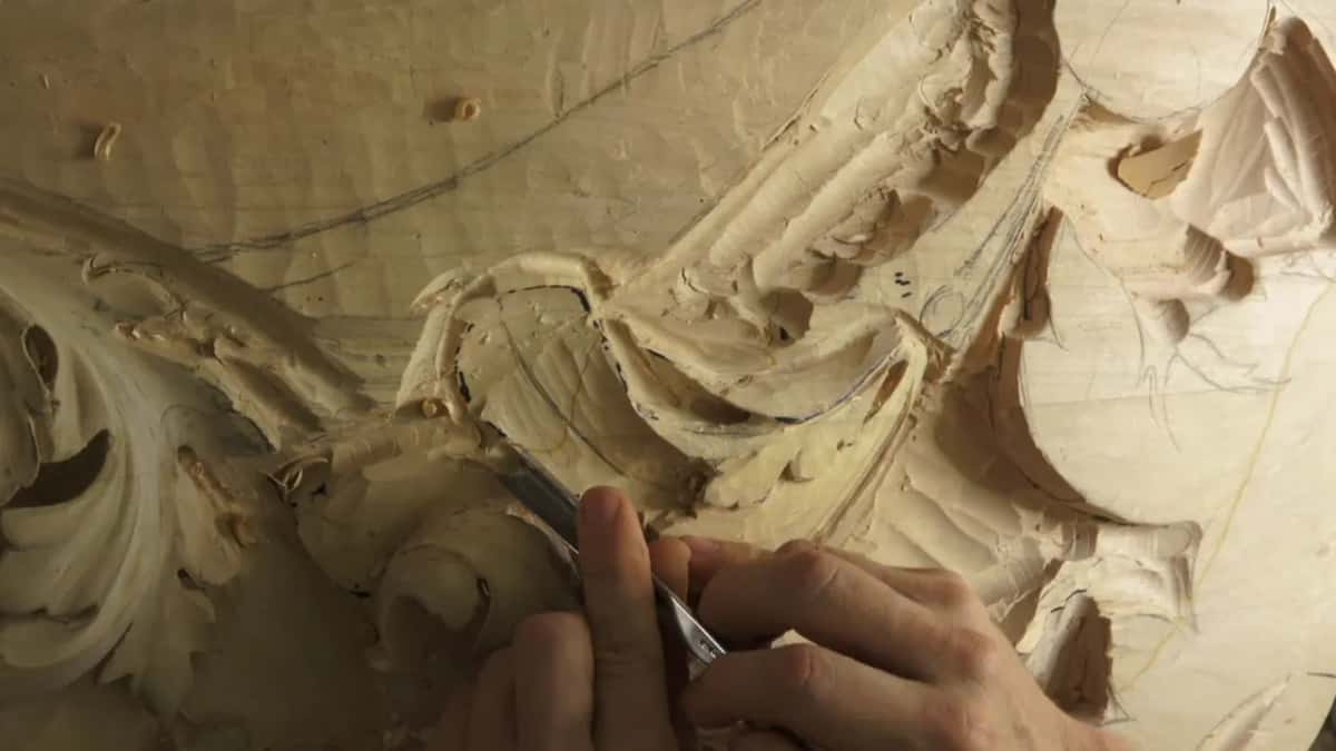 Two hands pushing a gouge along ink lines