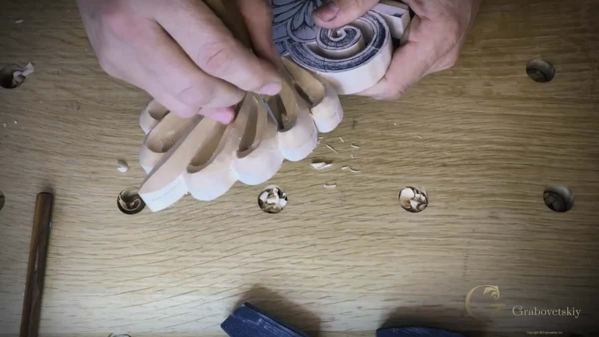 Shaped palm leaves held up close in two hands, chips on the bench