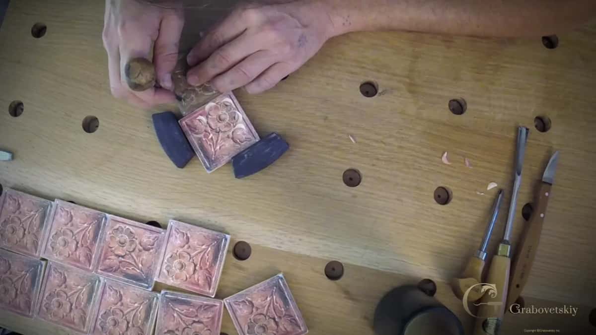 Paper patterns on a row of blocks while a small tool works the one held between two dark stops
