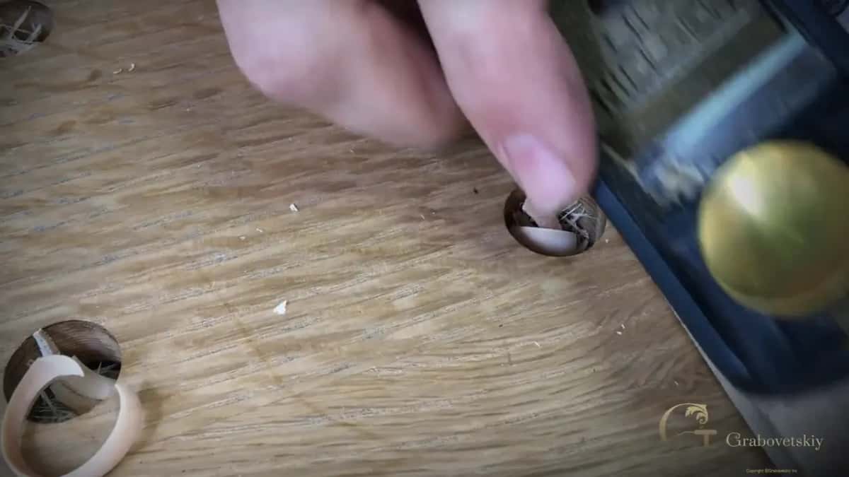 Fingers on a block plane, with curls of shaving on the bench and in a bench hole