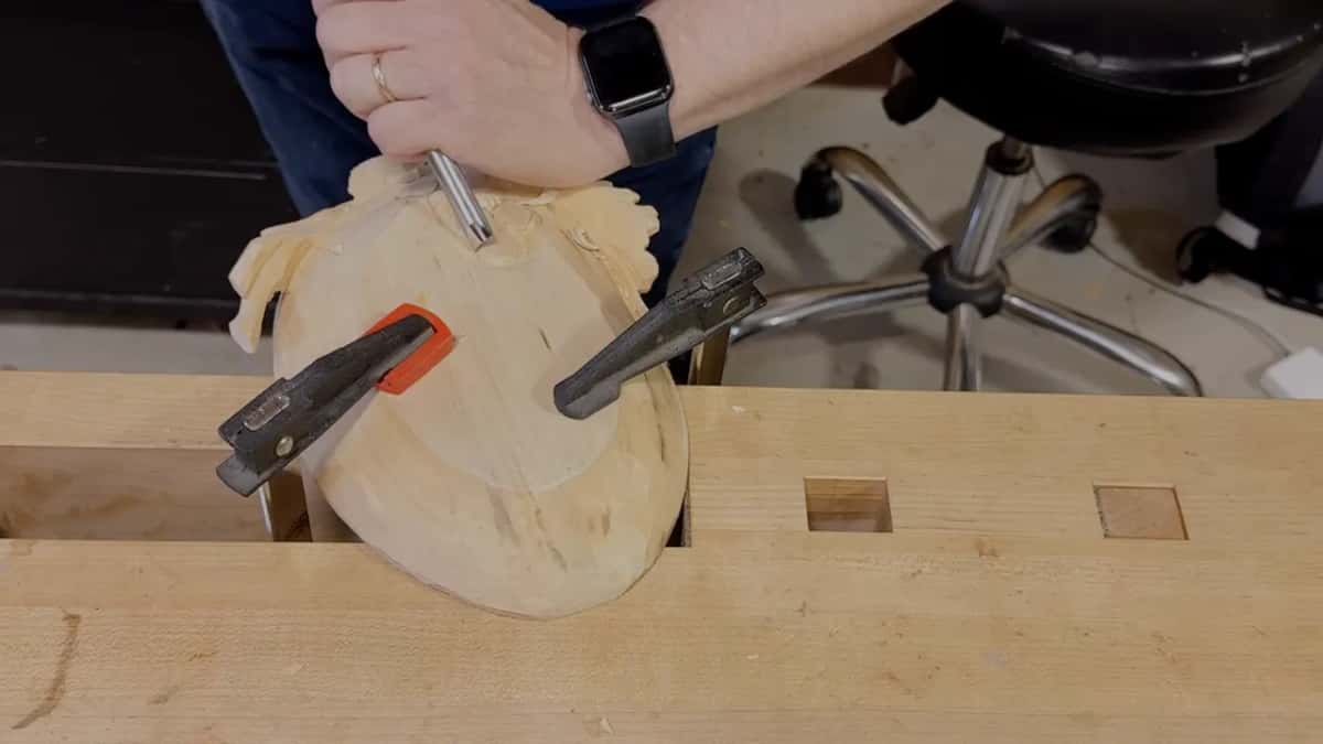 Tray clamped face down on the bench while one hand works its underside