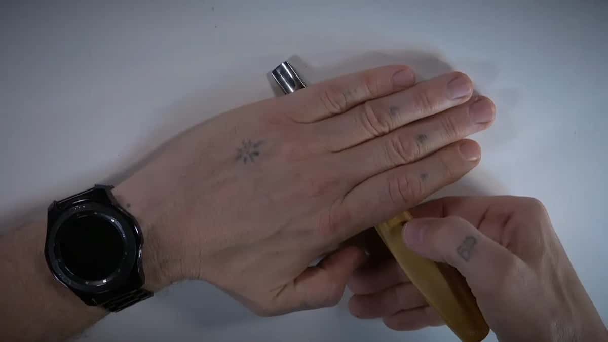 One hand laid flat over a pale handle while the other grips it from below on a white table