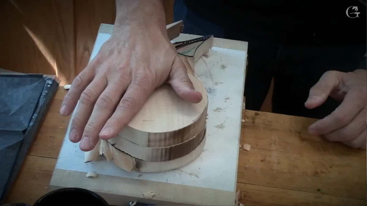 A hand presses the round top layer onto the glued block.