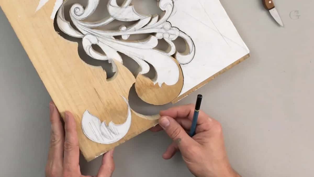 Paper pattern on the sawn board and on a leaf-shaped offcut, a pencil in one hand