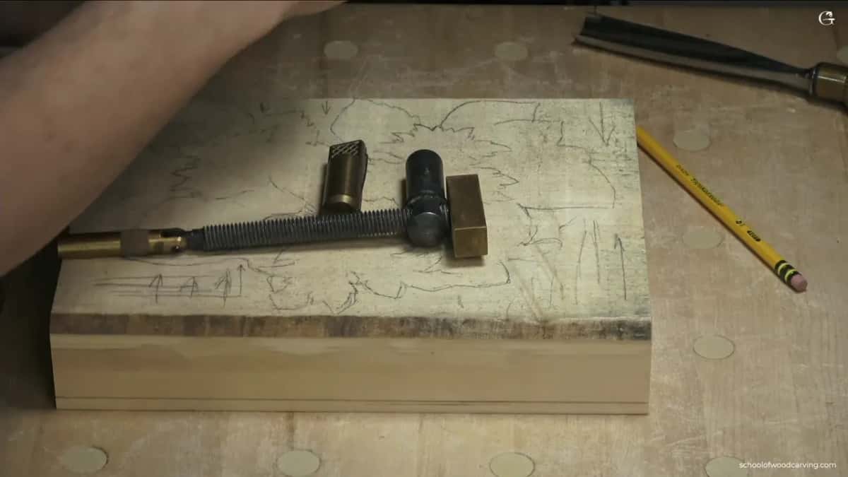 A screw clamp and two stops lie across the traced block, a pencil beside it