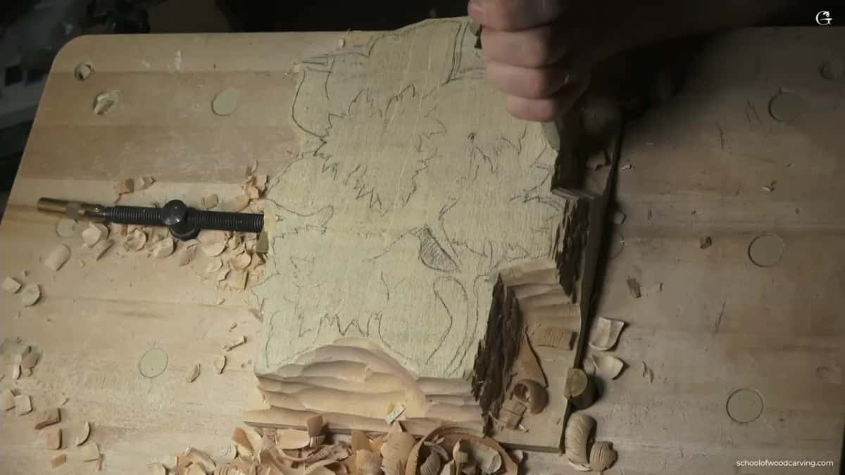 Fingers hold the tool at the right of the outline, stepped waste below