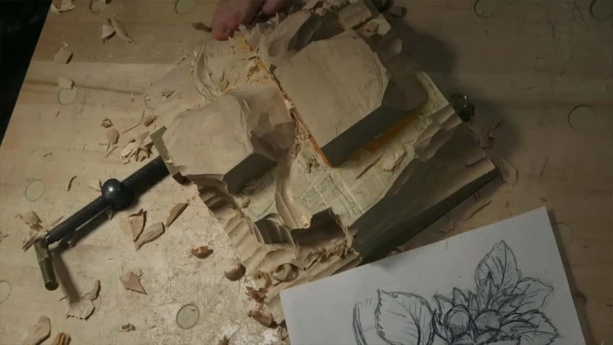Overhead view, a hand working at the top of the rough panel while the paper drawing waits beside it